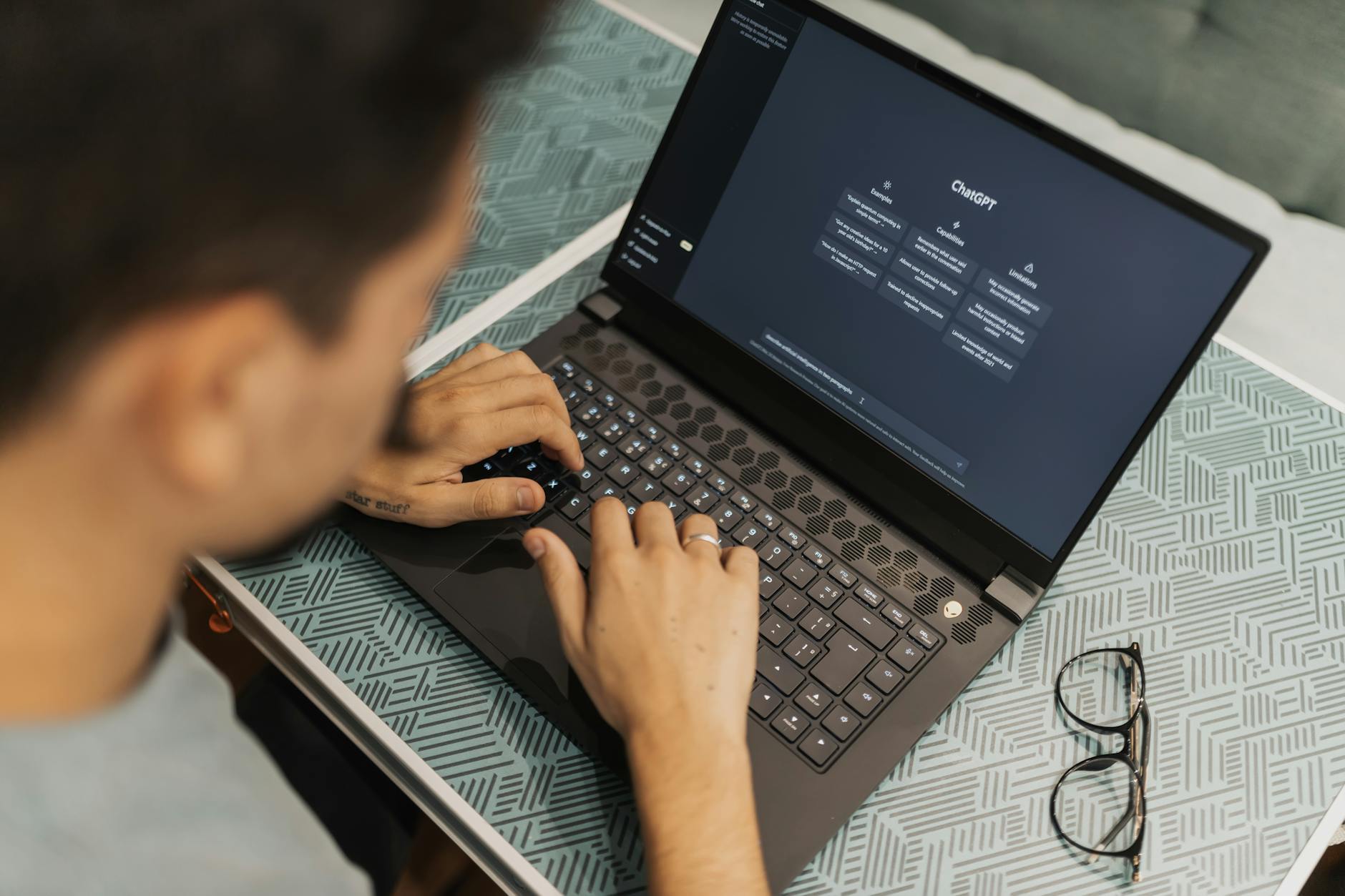 Programista w okularach pracuje na laptopie z otwartym narzędziem AI