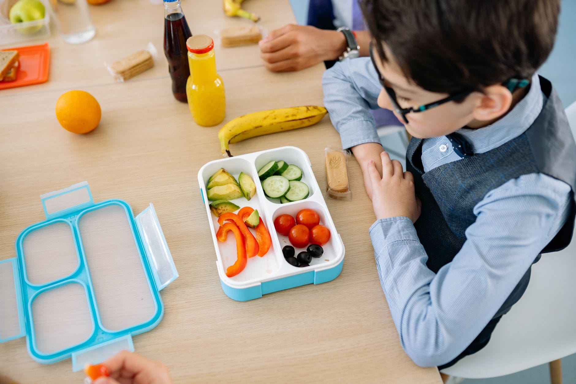 Chłopiec w szkole je zdrowy lunch z kolorowego lunchboxa