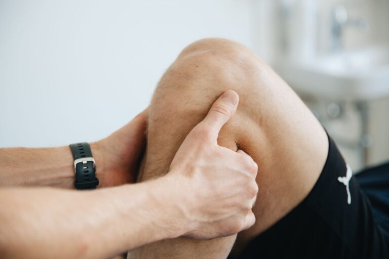 Fizjoterapeuta masuje kolano pacjenta podczas terapii